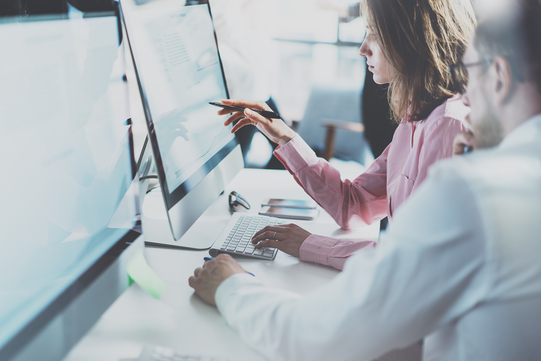 Office workers at desk looking at monitor - VOSS Insights monitoring and resolution banner