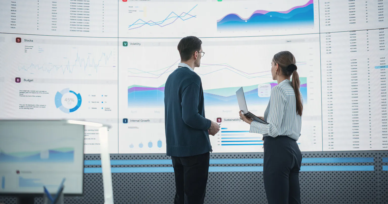 Understanding-employee-power-analytics-square-thumbnail Business man and woman discussing UC analytics in front of a large screen full of statistics