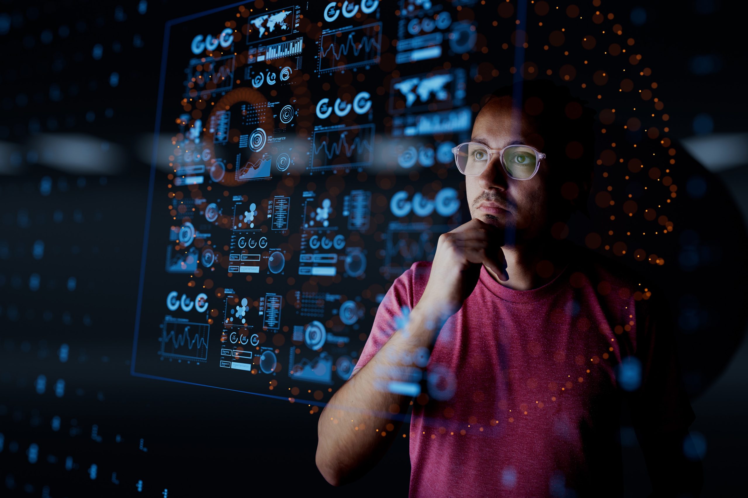 Dark background of Analyst looking at graphical data - used in VOSS blog for Maximizing Business Value with AI in UC: Cost Efficiency and New Opportunities