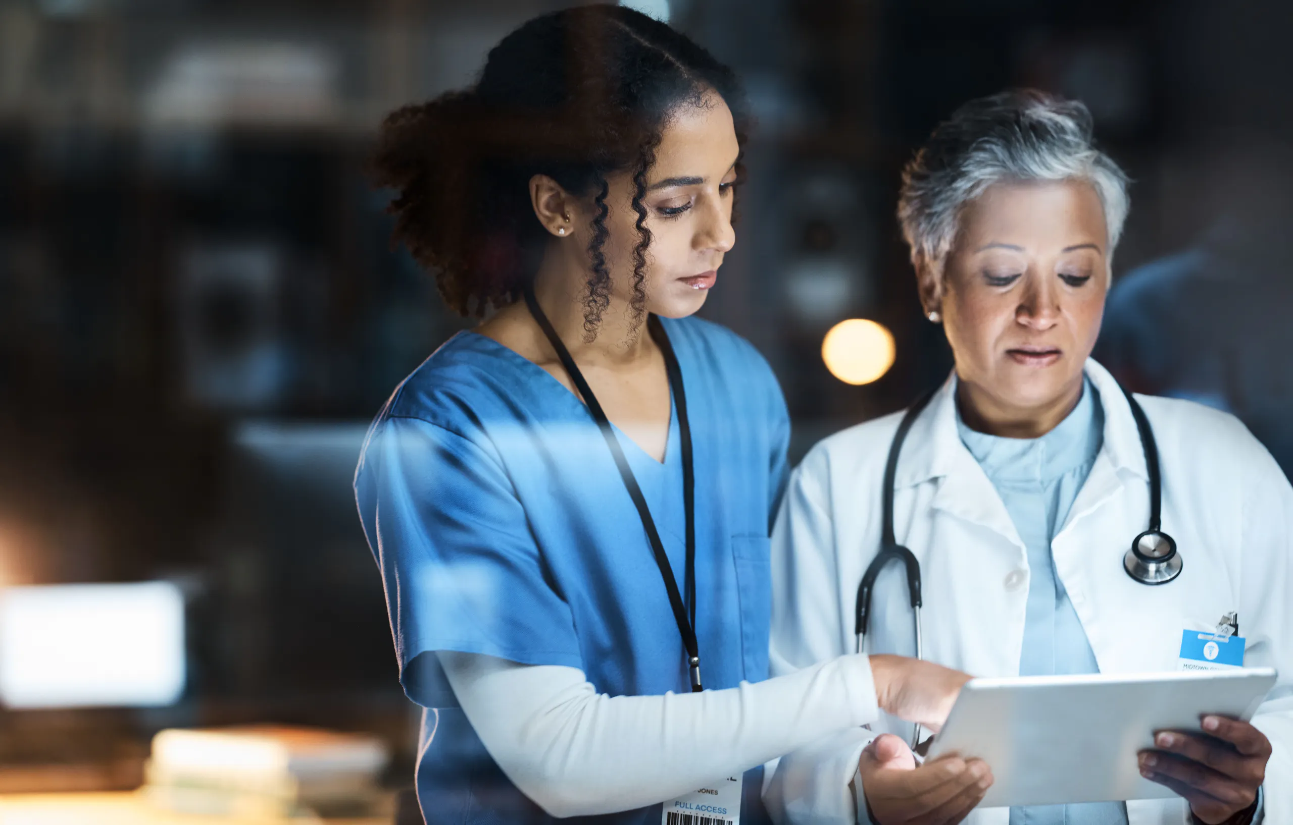 Healthcare professionals discussing treatment with a tablet Successful mergers and acquisitions | IT integration strategy for mergers and acquisitions | Post merger integration tool | M&A