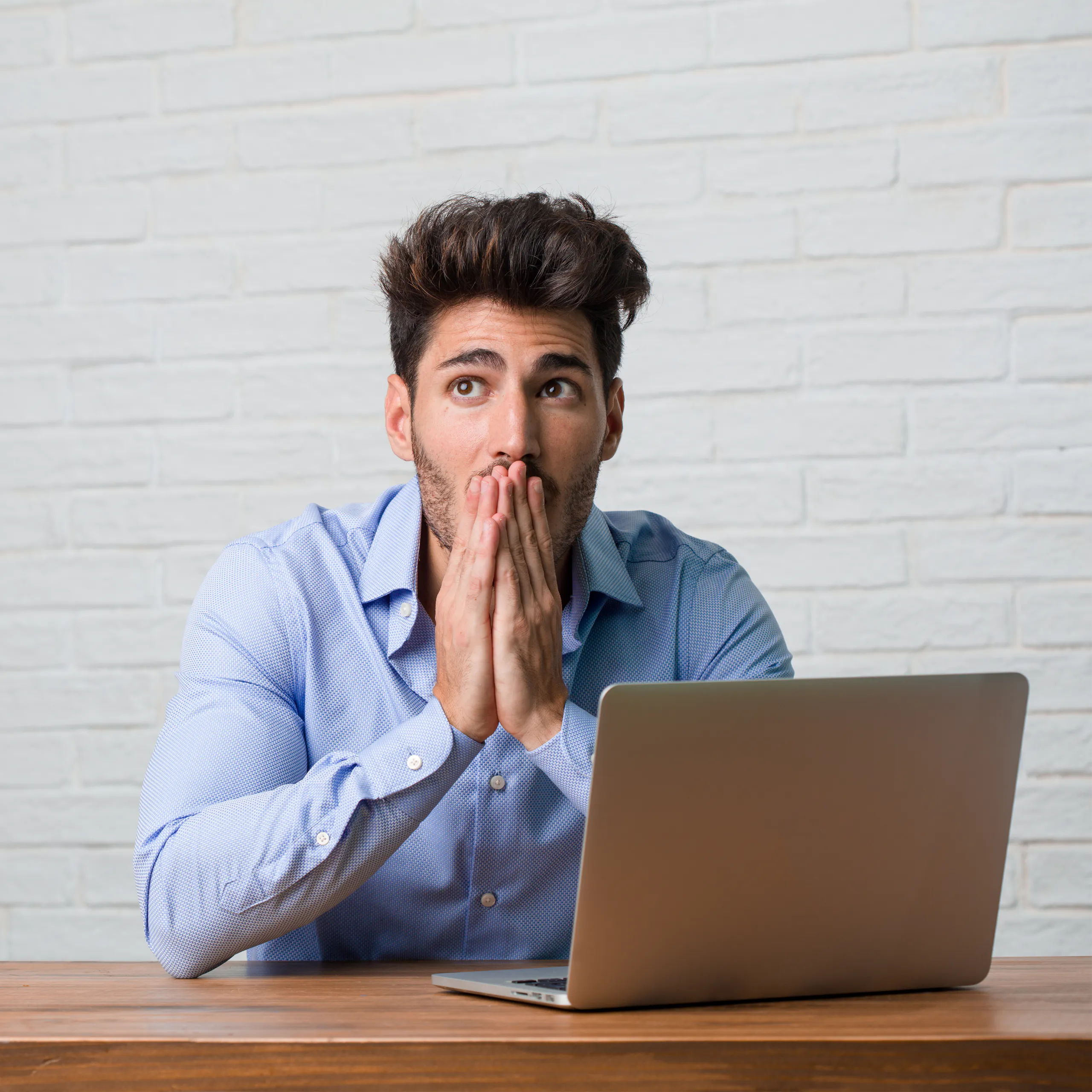 Are your people using the tools you’ve given them? Image shows Young business man sitting and working on a laptop covering mouth, symbol of silence and repression, trying not to say anything